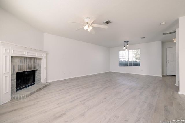 unfurnished living room with light wood-style flooring, a brick fireplace, visible vents, and a ceiling fan