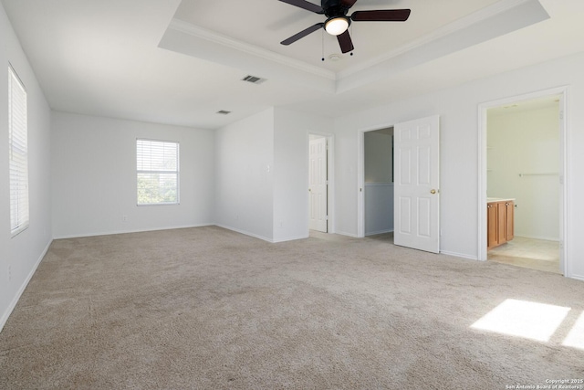 unfurnished bedroom with light carpet, baseboards, visible vents, a raised ceiling, and ornamental molding