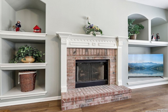 room details with a brick fireplace, baseboards, and wood finished floors