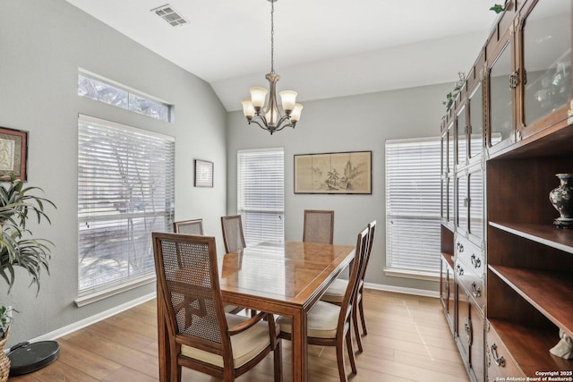 dining space featuring light wood-type flooring, an inviting chandelier, visible vents, and lofted ceiling