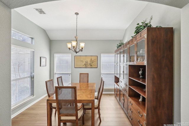 dining space with light wood-style floors, visible vents, vaulted ceiling, and a notable chandelier