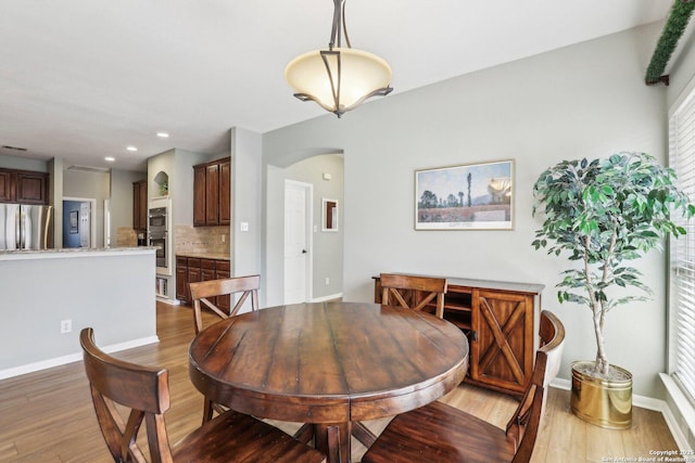 dining area featuring arched walkways, recessed lighting, wood finished floors, and baseboards