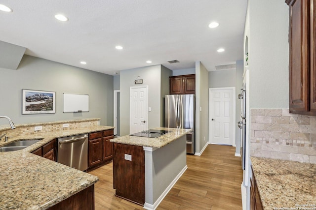 kitchen with light wood-style flooring, a kitchen island, stainless steel appliances, and a sink