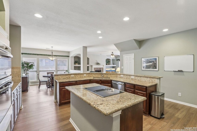 kitchen with dark wood finished floors, a spacious island, stainless steel appliances, a fireplace, and a sink