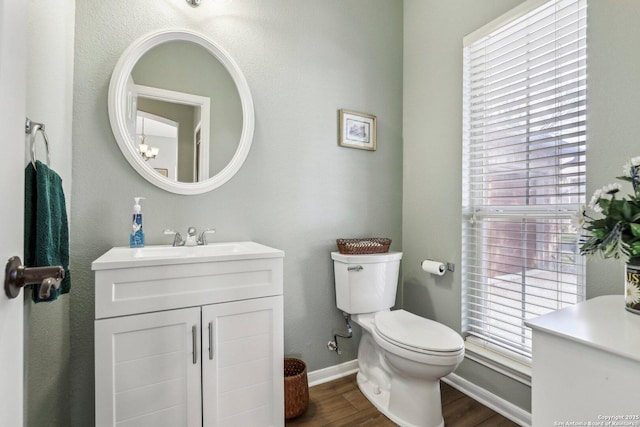 bathroom with a healthy amount of sunlight, vanity, toilet, and wood finished floors