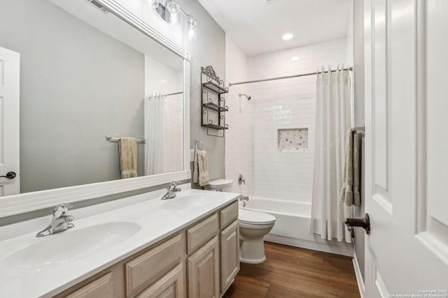 full bath featuring toilet, shower / bath combo with shower curtain, a sink, and wood finished floors