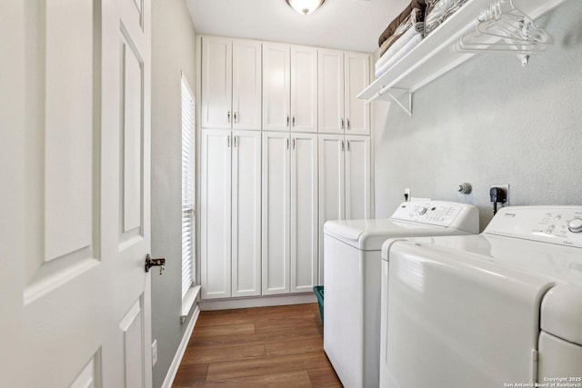 clothes washing area with cabinet space, dark wood-type flooring, and independent washer and dryer