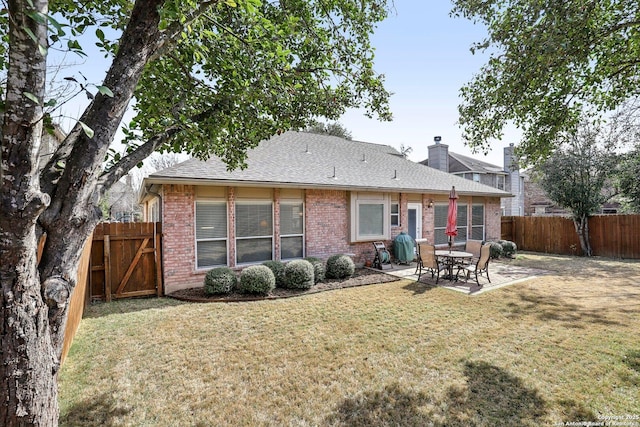 rear view of property featuring a yard, a patio, brick siding, and a fenced backyard