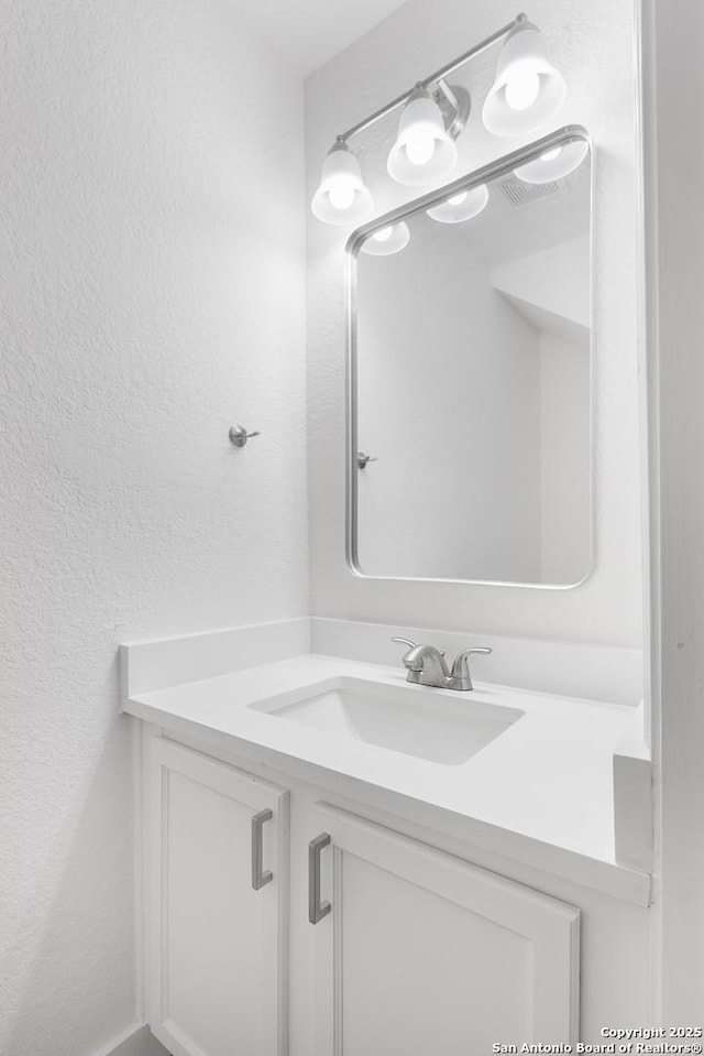 bathroom featuring a textured wall and vanity