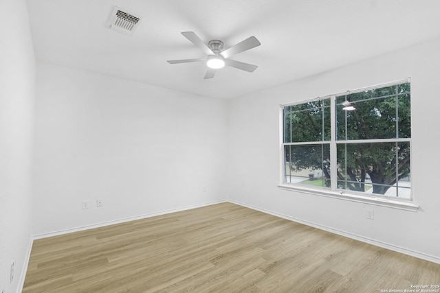 unfurnished room with a ceiling fan, visible vents, baseboards, and wood finished floors