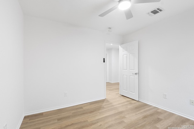 empty room with a ceiling fan, light wood-type flooring, visible vents, and baseboards