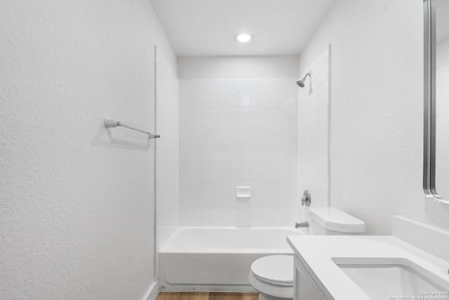 full bathroom with shower / bathtub combination, a textured wall, toilet, wood finished floors, and vanity