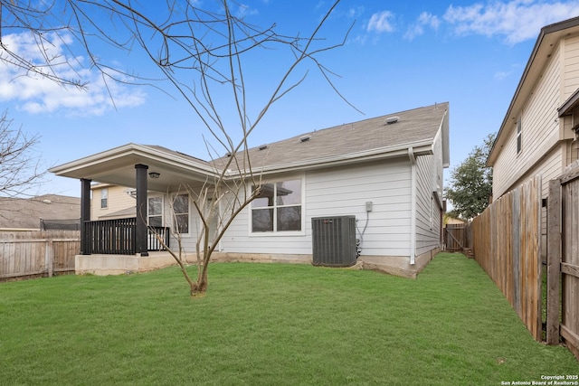 back of house featuring a fenced backyard, a shingled roof, a lawn, and central AC