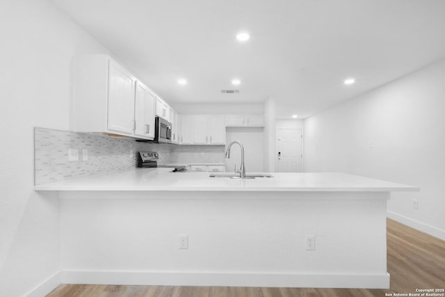 kitchen with a peninsula, a sink, visible vents, light countertops, and appliances with stainless steel finishes