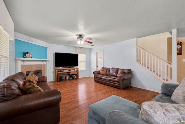 living room featuring stairs, a tile fireplace, a ceiling fan, and wood finished floors