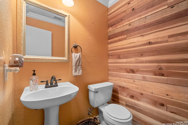 bathroom with visible vents, a textured wall, and toilet