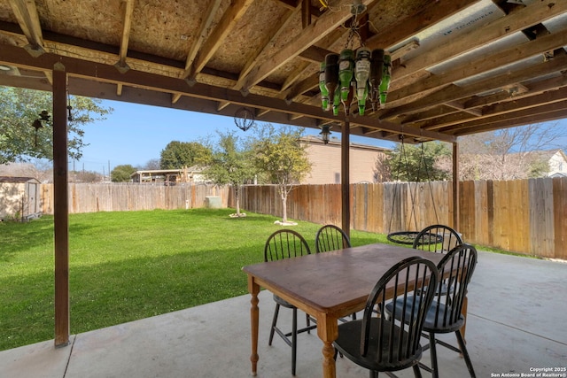 view of patio with a storage shed, a fenced backyard, outdoor dining area, and an outbuilding