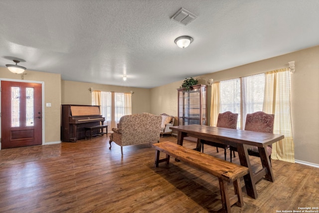 dining room with visible vents, a textured ceiling, baseboards, and wood finished floors