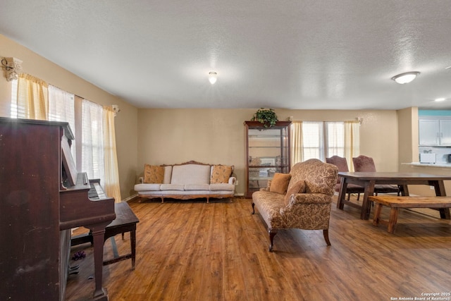 living room with a textured ceiling, baseboards, and wood finished floors