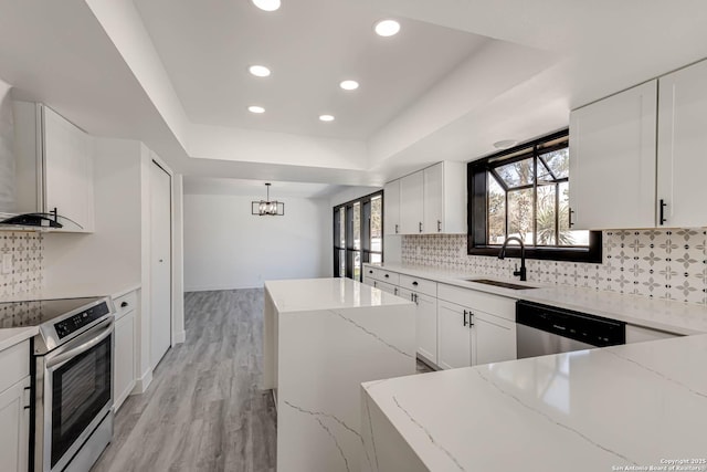 kitchen with tasteful backsplash, a raised ceiling, a kitchen island, stainless steel appliances, and a sink