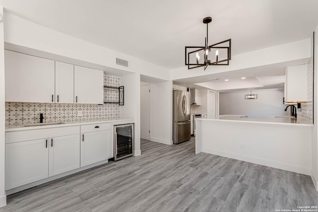 kitchen with stainless steel appliances, visible vents, white cabinetry, a sink, and beverage cooler