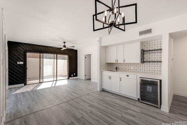 kitchen with light wood finished floors, visible vents, open floor plan, white cabinetry, and beverage cooler