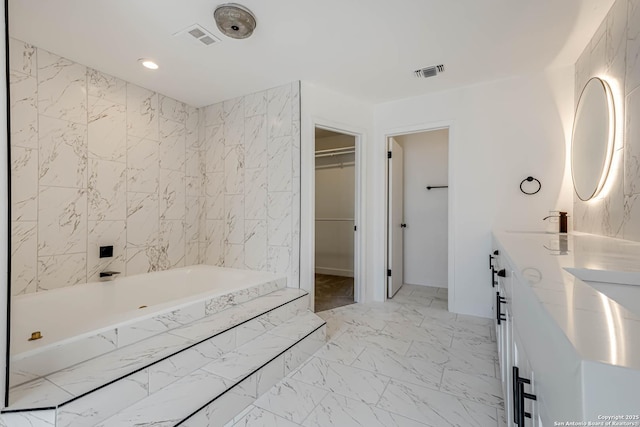 bathroom featuring a bathtub, marble finish floor, visible vents, and a spacious closet