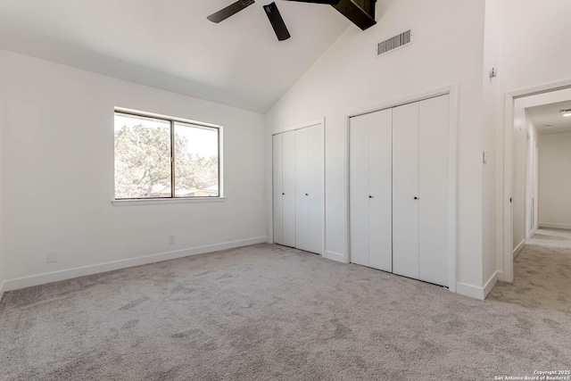 unfurnished bedroom with carpet floors, high vaulted ceiling, two closets, and visible vents