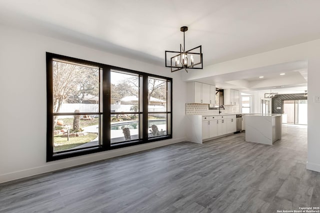 kitchen with a center island, backsplash, light wood-style floors, white cabinetry, and a sink