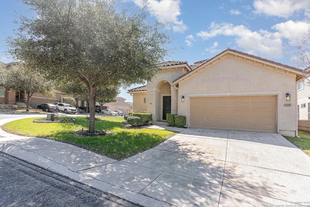 mediterranean / spanish home with a garage, a tile roof, driveway, stucco siding, and a front yard