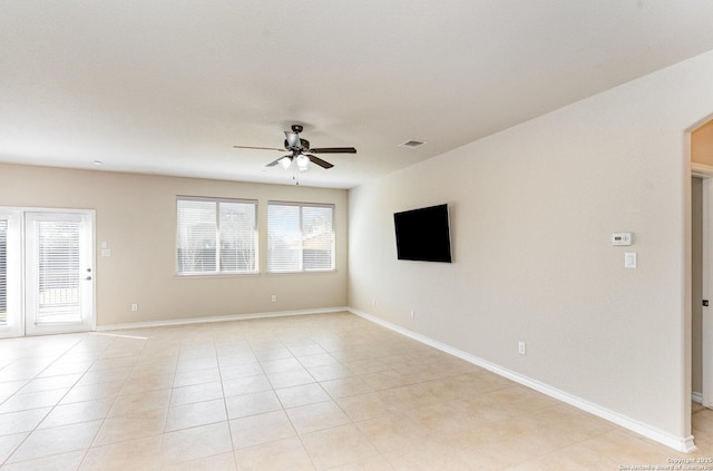 spare room featuring light tile patterned floors, ceiling fan, arched walkways, and baseboards