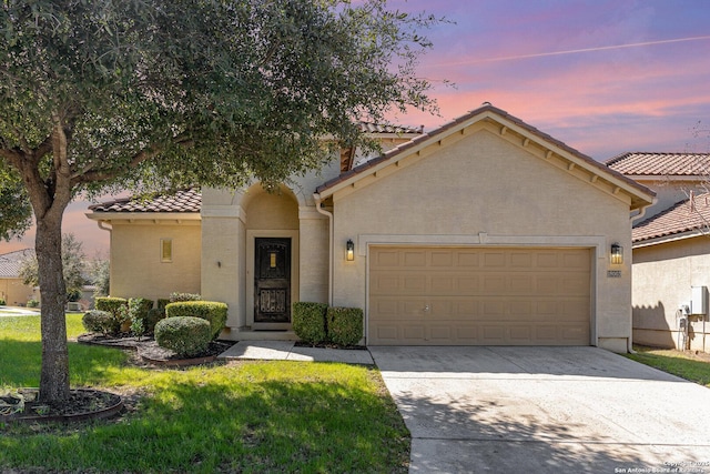 mediterranean / spanish-style house featuring a garage, concrete driveway, a tiled roof, and stucco siding