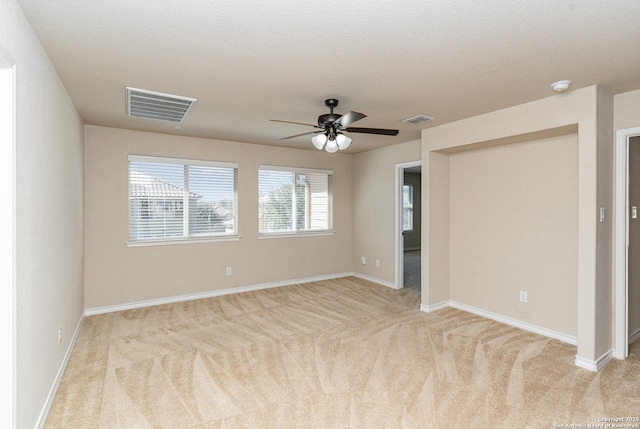 unfurnished bedroom featuring light colored carpet, visible vents, a textured ceiling, and baseboards