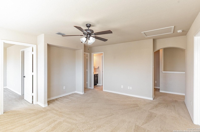 spare room featuring arched walkways, light carpet, visible vents, baseboards, and a ceiling fan