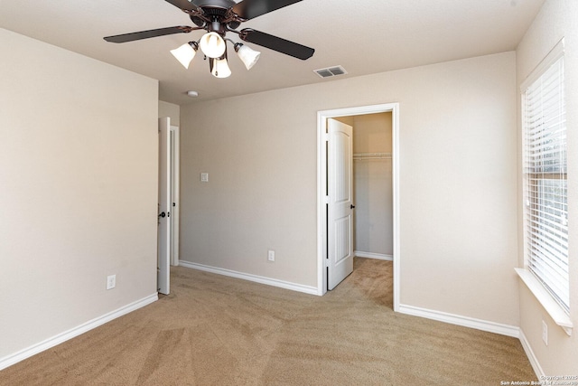 unfurnished bedroom featuring baseboards, a spacious closet, visible vents, and light colored carpet