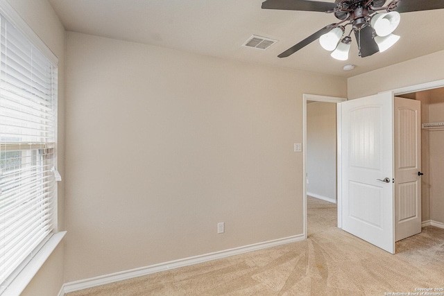 unfurnished bedroom featuring light carpet, baseboards, visible vents, and a ceiling fan