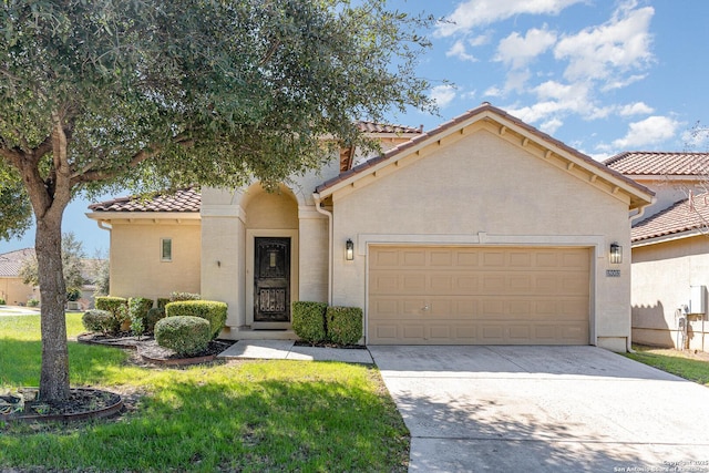 mediterranean / spanish-style house featuring a garage, concrete driveway, stucco siding, a tiled roof, and a front yard