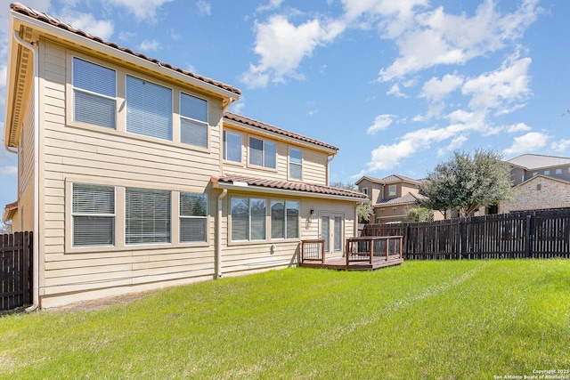 back of house with a deck, a tiled roof, a lawn, and a fenced backyard