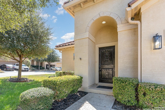 doorway to property with a tile roof and stucco siding