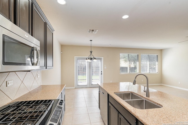 kitchen featuring visible vents, decorative backsplash, decorative light fixtures, stainless steel appliances, and a sink