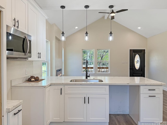 660 Skyline Dr, Bandera, TX 78003 - kitchen with a peninsula, a sink, white cabinets, stainless steel microwave, and dark wood finished floors
