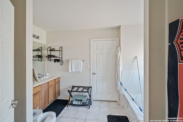 bathroom with marble finish floor, vanity, and a bath