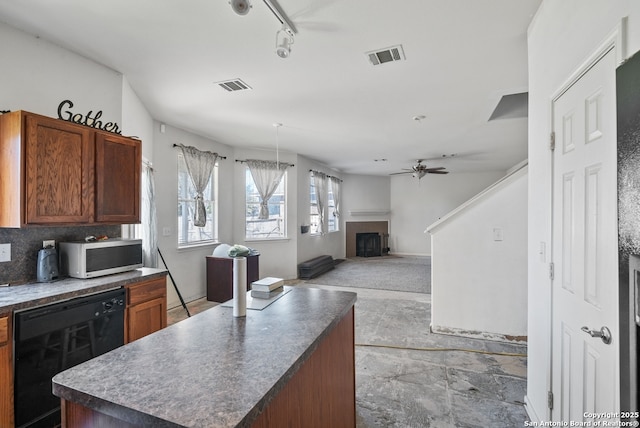 kitchen with a fireplace, visible vents, black dishwasher, stainless steel microwave, and dark countertops