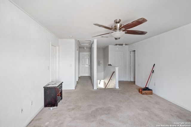 carpeted spare room with baseboards, attic access, visible vents, and a ceiling fan