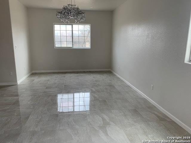 empty room featuring a notable chandelier and baseboards