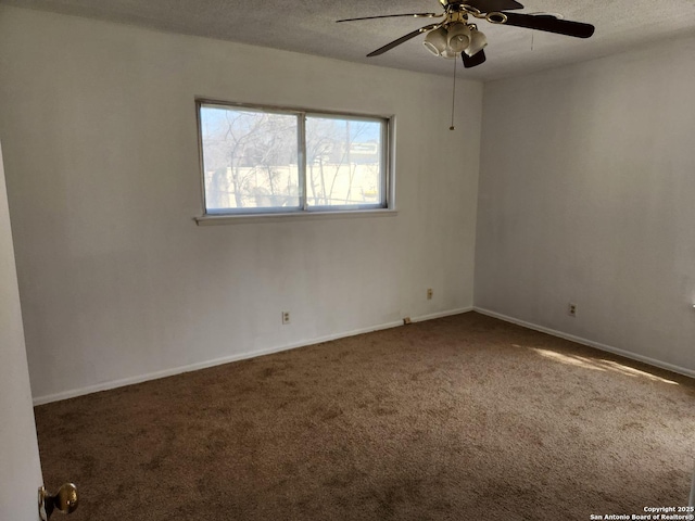 empty room with a textured ceiling, carpet floors, ceiling fan, and baseboards