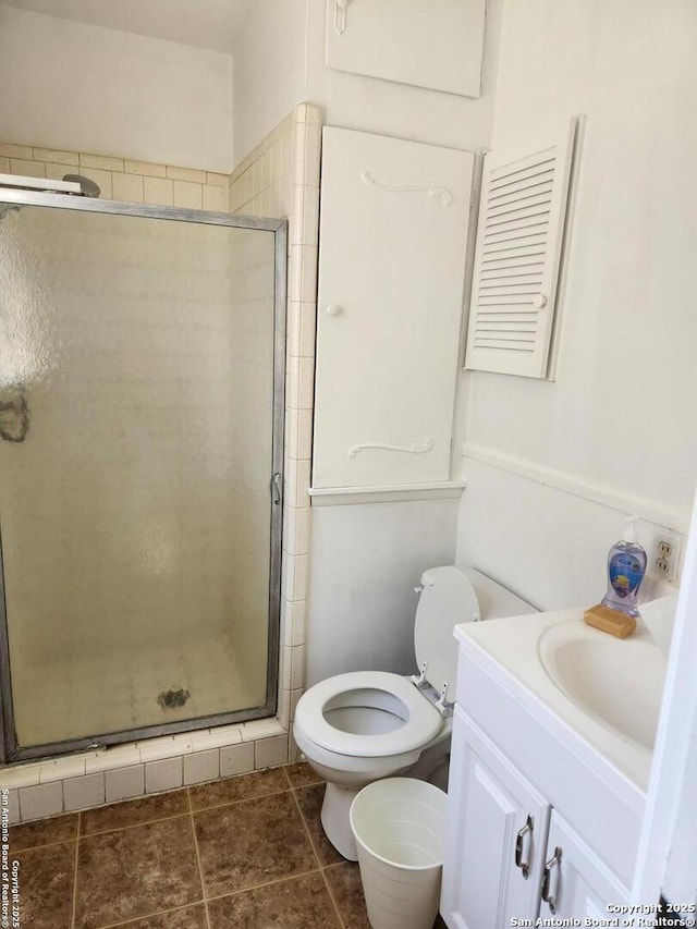 bathroom featuring tile patterned flooring, a shower stall, toilet, and vanity