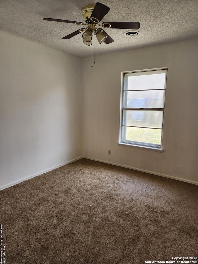 carpeted spare room with baseboards, visible vents, ceiling fan, and a textured ceiling