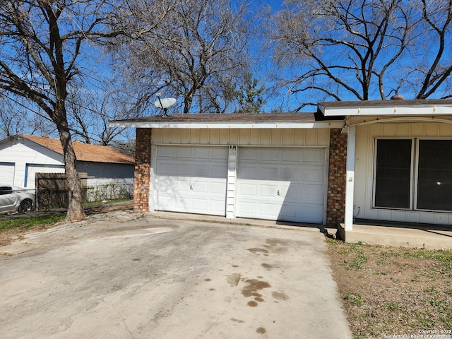 garage featuring concrete driveway and fence