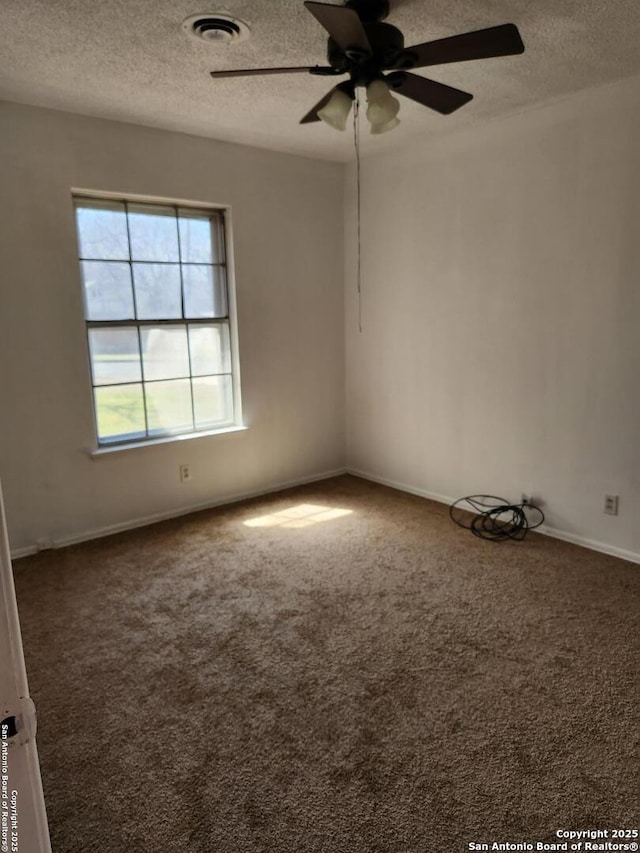 carpeted empty room featuring ceiling fan, a textured ceiling, visible vents, and baseboards